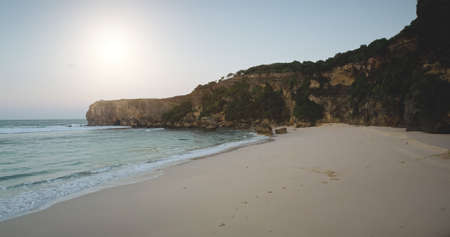 Sunlight sand beach at ocean bay waves aerial view. Amazing seascape with cliff coast and stones. Sumba island, Indonesia landscape at sunny summer day. Soft light sun shine over rock wallの写真素材