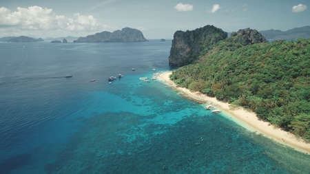 Cruise at tropical sea coast on boats, ships. Tourists relaxing and swim at shallow water near coastline. Green tropic jungle forest at sand beach. Cinematic paradise vacation tour for travelersの写真素材