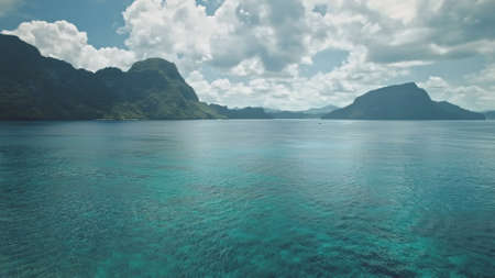 Panorama seascape with tropic islands aerial view. Lonely sail yacht at marine scape. Serene blue water with mountainous islets of El Nido, Philippines, Asia. Cinematic drone shotの写真素材