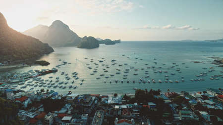 Ocean bay port with water transport at tropical cityscape. Majestic paradise resort with small vessels, buildings at sun rise at summer morning. Serene seascape with ships, boats at Philippines islandの写真素材