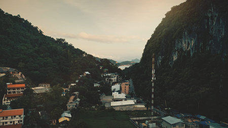Closeup aerial cityscape at tropical forest mountain ranges. Beautiful homes, lodges, trafic roads...