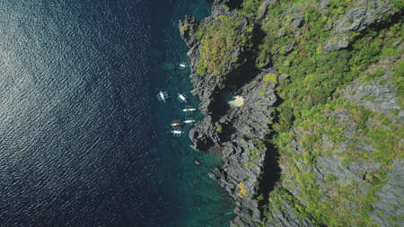 Top down green rock island harbor with passenger boats aerial view. Nobody nature landscape of tropic paradise resort at Philippines Archipelago. Amazing summer ocean cruise sceneryの写真素材