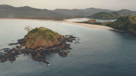 Rock island at sea bay aerial. Nobody tropic nature seascape. High exotic trees at mountain hills. Green landscape at paradise resort. Summer cruise on boat at ocean gulf. Cinematic drone shotの写真素材