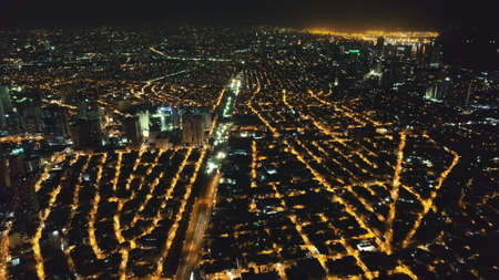 Aerial slow motion cityscape at night. Illuminated streets of Manila downtown at traffic city route. Urban transport at highway. Modern buildings, skyscrapers with neon lights. Drone unveiling shotの写真素材