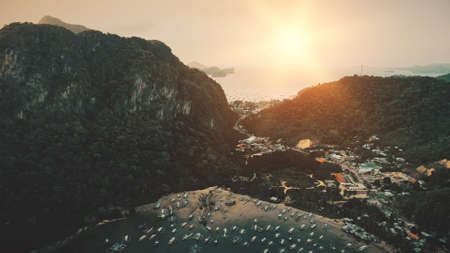 Port town at tropical paradise island. Amazing cityscape at mounts with exotic forest. Small cottages, buildings at roads on mountain ranges. Greenery nature of Asia urban scenery. Cinematic soft shotの写真素材
