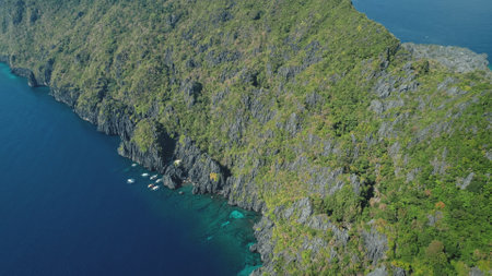 Green rock coast of mountain island at ocean bay water aerial. Nobody seascape with tropical nature of Palawan with boats at cliff sea shore. Summer cruise tour at El Nido isle, Philippine archipelagoの写真素材