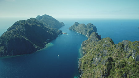 Vessels at sea bay of tropic islands aerial view. Amazing blue seascape at hilly isles with wild nature. Marine scenery of water transport with summer travel concept. Cinematic soft light drone shotの写真素材