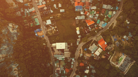 Top down slow motion aerial cityscape with lodges, homes, buildings roofs and roads at green tropic forest. Epic urban scenery of Palawan resort at summer. Cinematic soft sun light drone top-down shotの写真素材