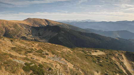 Aerial mountain ridges. Rock mount top at high altitude. Nobody nature landscape. Green grass at brown peak. Mountaineering vacation at autumn. Carpathians, Ukraine, Europe. Cinematic drone shotの写真素材