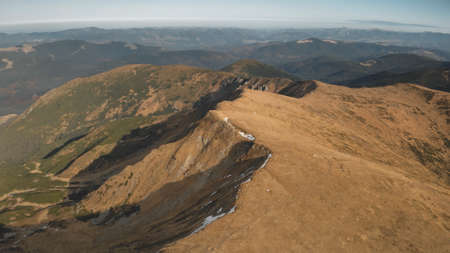 Aerial path on mountain top at high altitude. Nobody nature landscape. Autumn grass at rock hills, peak. Fir forest at ranges. Mountaineering scene. Cinematic Carpathians mounts, Ukraine, Europeの写真素材