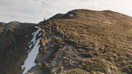 Slow motion aerial tourists hike at mountain. Travelers at nature landscape. Snow, grass, moss at autumn. People mountaineering travel lifestyle. Carpathian mount ridges, Ukraine, Europe. Tourism shotの写真素材