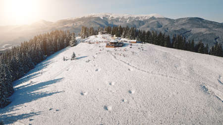 Aerial sun resort at mountain forest. Tourists landmark at nature landscape. Frost and snow at sunny day. Ski slope. People active sport. Vacation at Carpathian mounts, Bukovel, Ukraine, Europeの写真素材