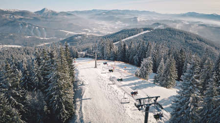 Resort at snow mountain aerial. Ski escalator at pine forest. Tourist landmark. Active winter sport. Travel and tourism concept. Cinematic vacation. Carpathians mounts, Bukovel, Ukraine, Europeの写真素材