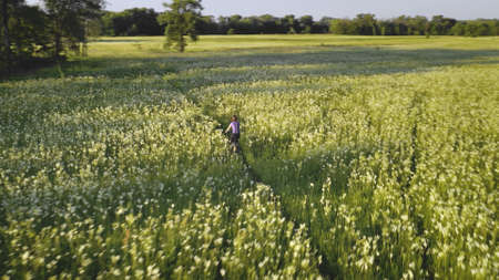 Girl cycling on bicycle at sun meadow aerial. Countryside nature landscape. Active sport. Bloom flowers at valley. Green grass field at summer sunny day. Rural journey. Kyiv city, Ukraine, Europeの写真素材