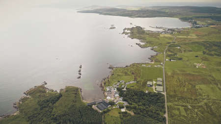 Top down factory at seascape. Aerial nobody nature landscape. Green forest at grass valley. Countryside fields, pastures at sea bay of port town Ellen, Islay Island, United Kingdom, Europeの写真素材