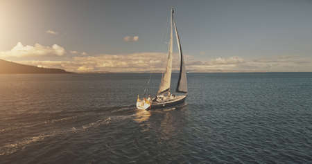 Aerial yacht regatta race at open sea. White sail boat at summer sunlight day. Amazing seascape of ocean waters at sun reflections. Serene water at cinematic relax and calm waterscapeの写真素材