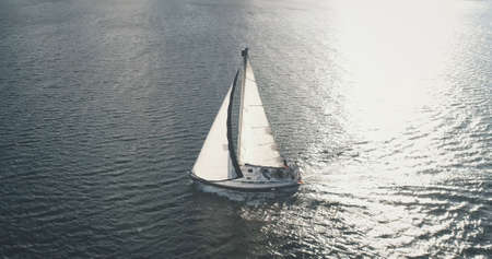 Sun light at sea bay with luxury yacht reflection aerial. Epic passenger sailboat cruise at open ocean. Tourism and travel lifestyle. Summer vacation scenery at sunshine. Cinematic seascapeの写真素材