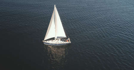 Yacht regatta race at ocean bay with seagull flying aerial. Sun reflect at Brodick Gulf, Scotland, Europe. Sail boat at open sea. Sailboat at summer cruise. Luxury vacation at marineの写真素材