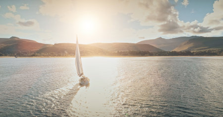 Sailing yacht in wind waves at Arran Island sea bay in Scotland. Amazing seascape at Brodick port city. Lonely sail boar race at sun shine with fluffy clouds. Serene water scape and transportationの写真素材