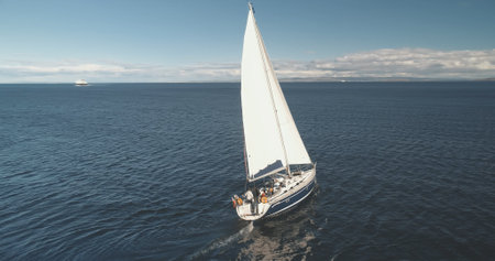 Luxury yacht at open sea racing under sails aerial. Amazing seascape of ocean bay with ship. Epic sail boat at Brodick pier harbor, Arran island, Scotland, Europe. Cinematic summer cruiseの写真素材