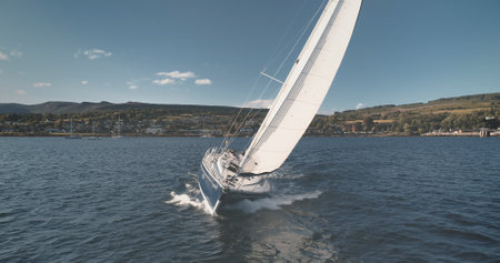Yacht sailing at ocean bay aerial. Summer nobody nature seascape. Sailboat at sun reflection. Port town cityscape at sunny mountain shore. Amazing landscape. Epic cruise at open sea. Marine vacationの写真素材
