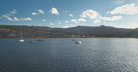 Regatta on luxury yachts aerial. Sail boats cruise at ocean bay in Brodick harbor, Arran Island, Scotland, Europe. Cinematic seascape of summer vacation sunny day. Panorama drone shotの写真素材
