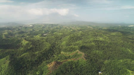 Misty green rainforest mounts aerial view at Legazpi, Philippines, Asia. Heavy rain clouds at sky over Filipino mountains ranges. High Asian greenery trees and grass at soft light drone shotの写真素材