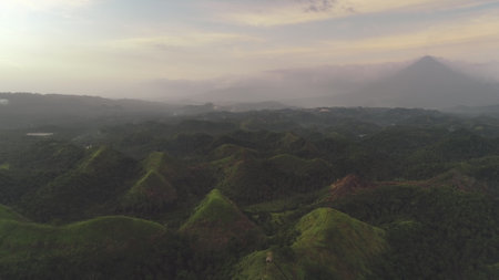 Green mountains ranges at fog with abudant tropic greenery rainforest. Calmness and relaxation of misty tropical nature landscape. Asian exotic scenery at cloudy sky in dramatic tonesの写真素材