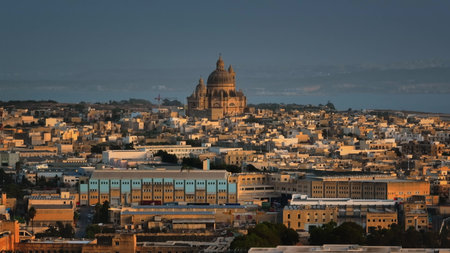 Malta, Comino island: Gozo Cathedral Church of Saint John the Baptist, Rotunda of Xewkija rising over Victoria warm toned cityscape, in golden sunset light, picturesque view of urban landscapeの写真素材