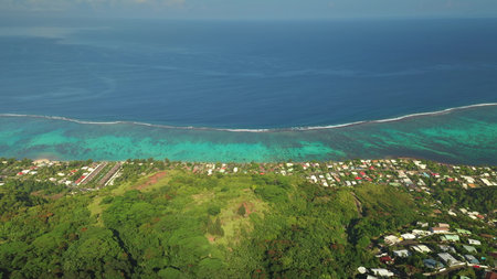 Breathtaking aerial view capturing Tahitis vibrant coastline, with turquoise waters lapping colorful coral reefs and lush vegetation framing charming homes along the shore. Exotic travel vacationの写真素材