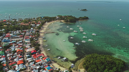 Stunning aerial view of a tropical paradise showcasing the vibrant cultural landscape of Malapascua Island, Philippines, with colorful houses, traditional boats, and crystal-clear turquoise watersの写真素材