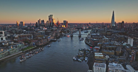 Tower Bridge and The Shard are reflecting on River Thames at sunset, creating a stunning cityscape view of Londons business district. Evening city skyline under vibrant sky. Drone flightの写真素材