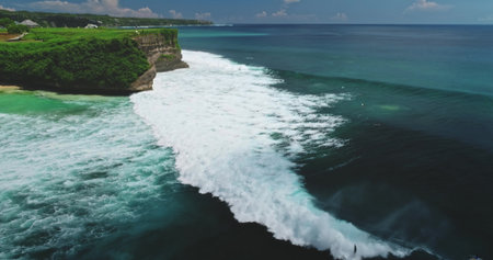 Stunning aerial view of big waves rolling to the shore at Dreamland Beach on a beautiful sunny day, Bali, Indonesia, with surfers enjoying the powerful wavesの写真素材