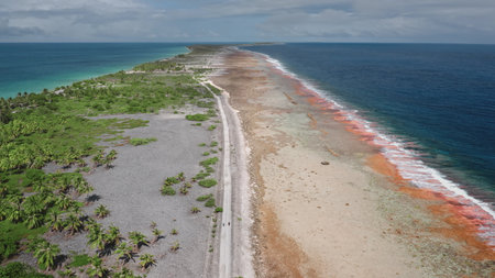 French Polynesia, Rangiroa island: Aerial view capturing Tiputa motus road dividing Rangiroa lagoon and Pacific Ocean, featuring vibrant corals and white sand beaches. Drone flightの写真素材