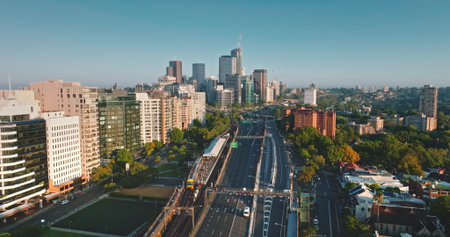 Sydney skyline city architecture, buildings and busy infrastructure, multi-lane highway and train lines in warm morning light under a clear blue sky. Australia modern cityscape. Aerial drone footageの写真素材