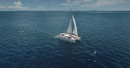 Catamaran sailing in the ocean near Kuata island, Fiji, aerial drone capturing the vastness of the sea and the beauty of the tropical islands in the background. Drone flightの写真素材