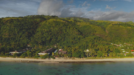 Breathtaking aerial view of a tropical resort nestled between lush green hills and the crystal-clear turquoise waters of the pacific ocean, showcasing the idyllic beauty of Tahitiの写真素材