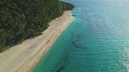 Capturing aerial drone of a tropical beach merging with turquoise waters on a sunny day, surrounded...