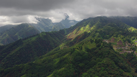 Aerial view of dramatic clouds rolling over the lush green tropical mountains and valleys, with...