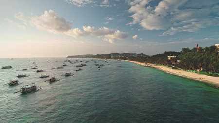 Aerial view capturing Cagban Beach at sunset, featuring traditional Philippine bangkas floating on...