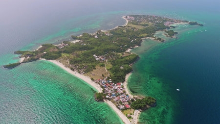 Aerial view of Malapascua Island in the Philippines, featuring vibrant turquoise waters, lush tropical vegetation, and colorful houses along the picturesque coastlineの写真素材