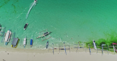 Aerial view of White Beach in Boracay, Philippines, featuring iconic paraw sailboats in turquoise...