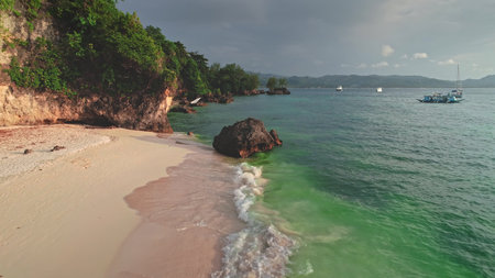Crystal-clear turquoise water gently washes the pristine white sand of Cagban Beach, Boracay Island,...