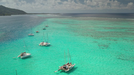 Breathtaking aerial view capturing catamarans moored in shallow, turquoise waters beside a tropical...