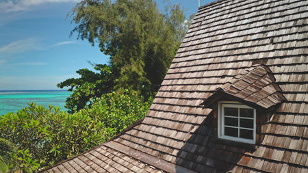 Wooden shingle roof with a dormer window, overlooking a breathtaking tropical beach with turquoise...