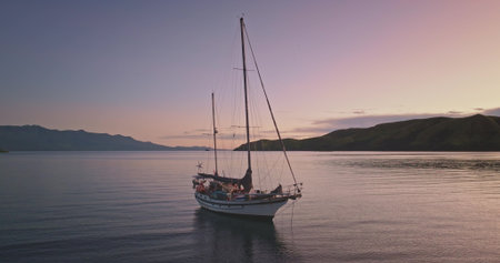 Romantic purple hues sky during sunset, casting a serene glow over calm sea waters. An anchored...