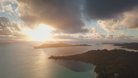 Bora Bora island with turquoise lagoon, mountains and clouds reflecting golden light of amazing colorful sunrise. Tropical island, beautiful landscape of untouched nature. Travel. Aerial drone flightの写真素材
