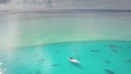 A stunning view sailboat gently bobbing on crystal clear turquoise waters. Surrounding the boat,...