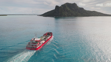 Red cargo ship deliver bulk carrier to exotic remote places, Maupiti, French Polynesia. Big boat...