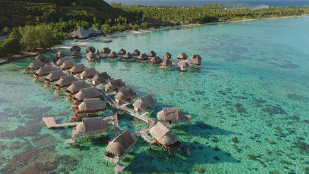 Breathtaking beauty of tropical island resort, overwater bungalows rows perched above vibrant...